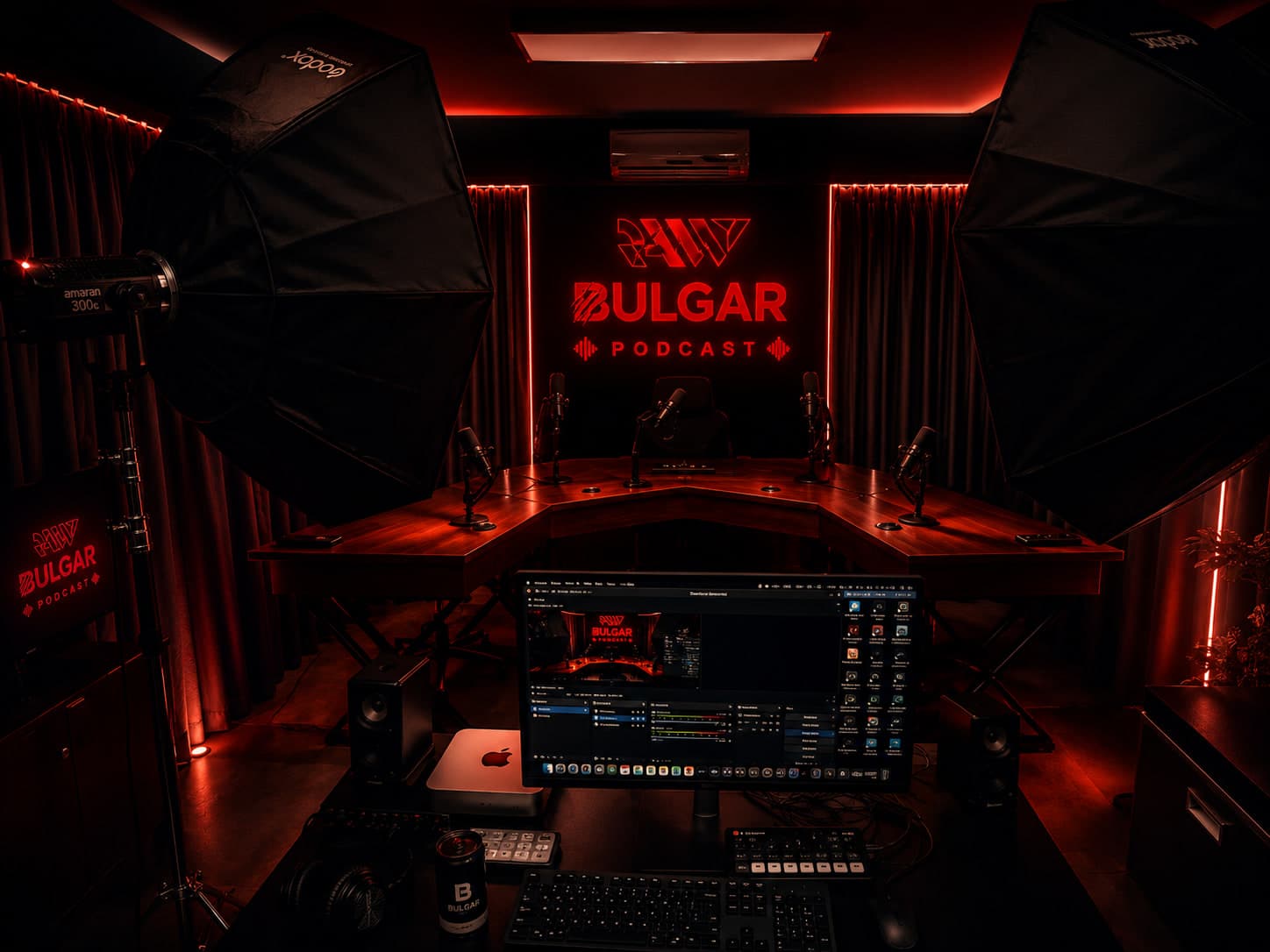 The studio: a curved four-seat desk with broadcast microphones and softboxes either side, lit red beneath a neon RAW BULGAR PODCAST sign.